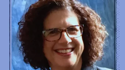 A headshot of a smiling woman with glasses.