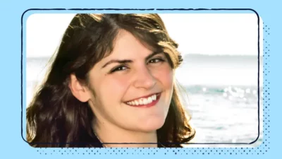 A headshot of a smiling woman with the ocean in the background.