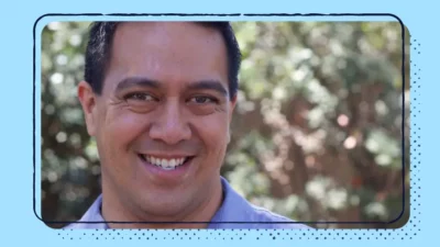 A headshot of a smiling man outdoors.