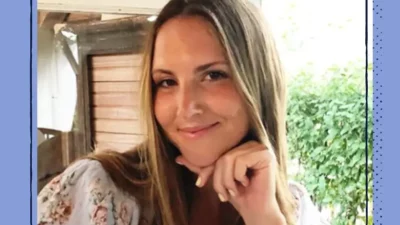 A smiling woman in a flowery shirt outdoors.