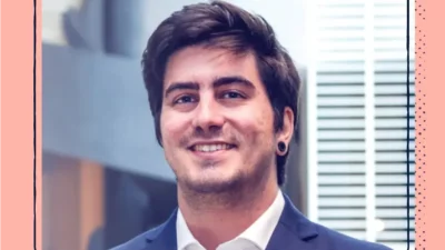 A headshot of smiling man in a suit with dark hair.