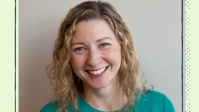 A headshot of a smiling woman in a green shirt.