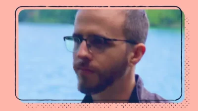 A headshot of a man in front of a body of water.