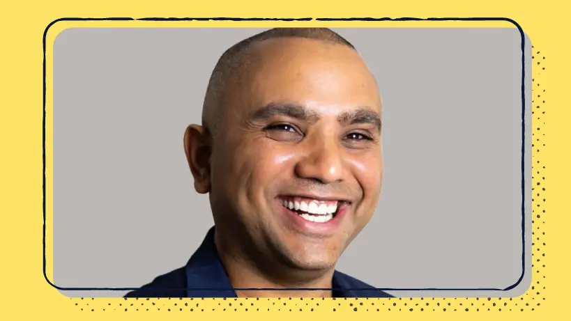 A headshot of a smiling man on a yellow background.