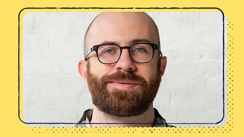 A headshot of a man with a beard and glasses.