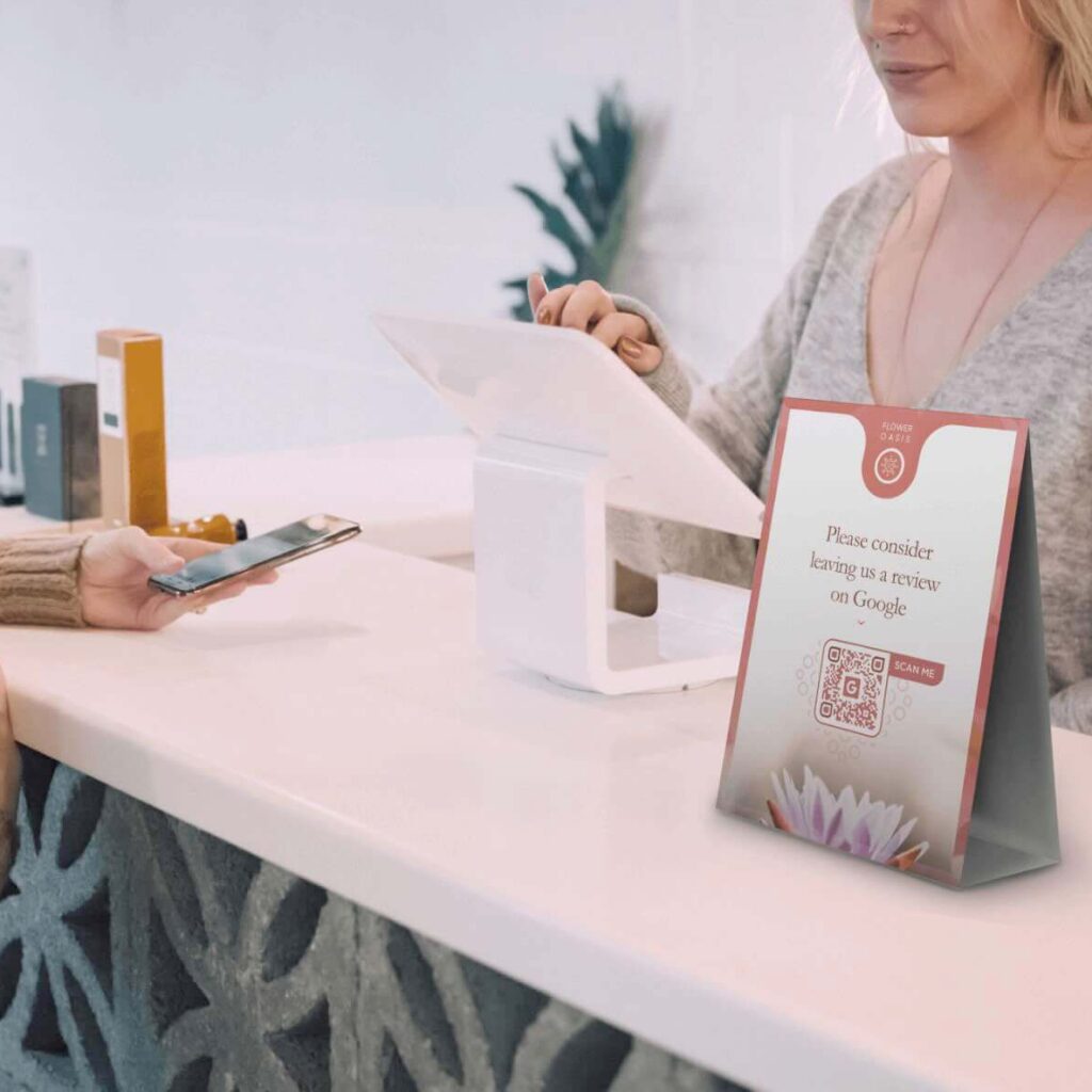 A table tent  with a QR Code on it on a counter between a customer and a retail clerk.