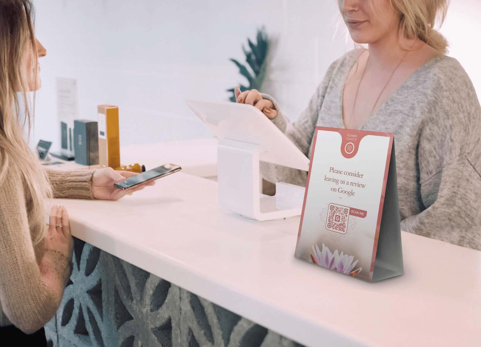 A table tent with a QR Code on it on a counter between a customer and a retail clerk.